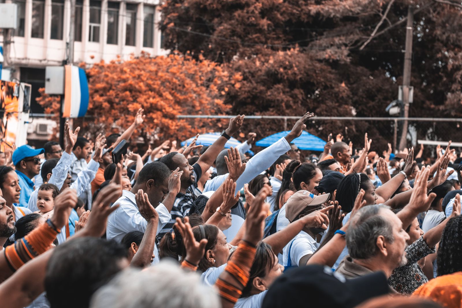 People worshipping with hands raised at an outdoor gathering